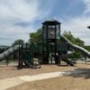 A large commercial playground with wide walkways and mulch around it. There are three large slides.